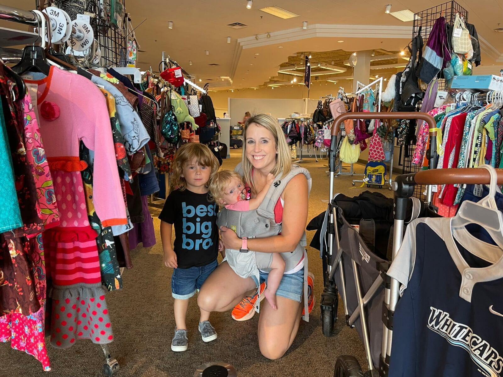 A mom and her child hug in between two rows of little girl clothes