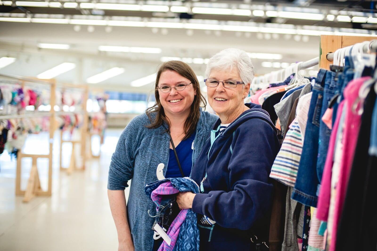 Grandmom, mom and baby in a carrier gather together and flash a smile as they shop for baby items.