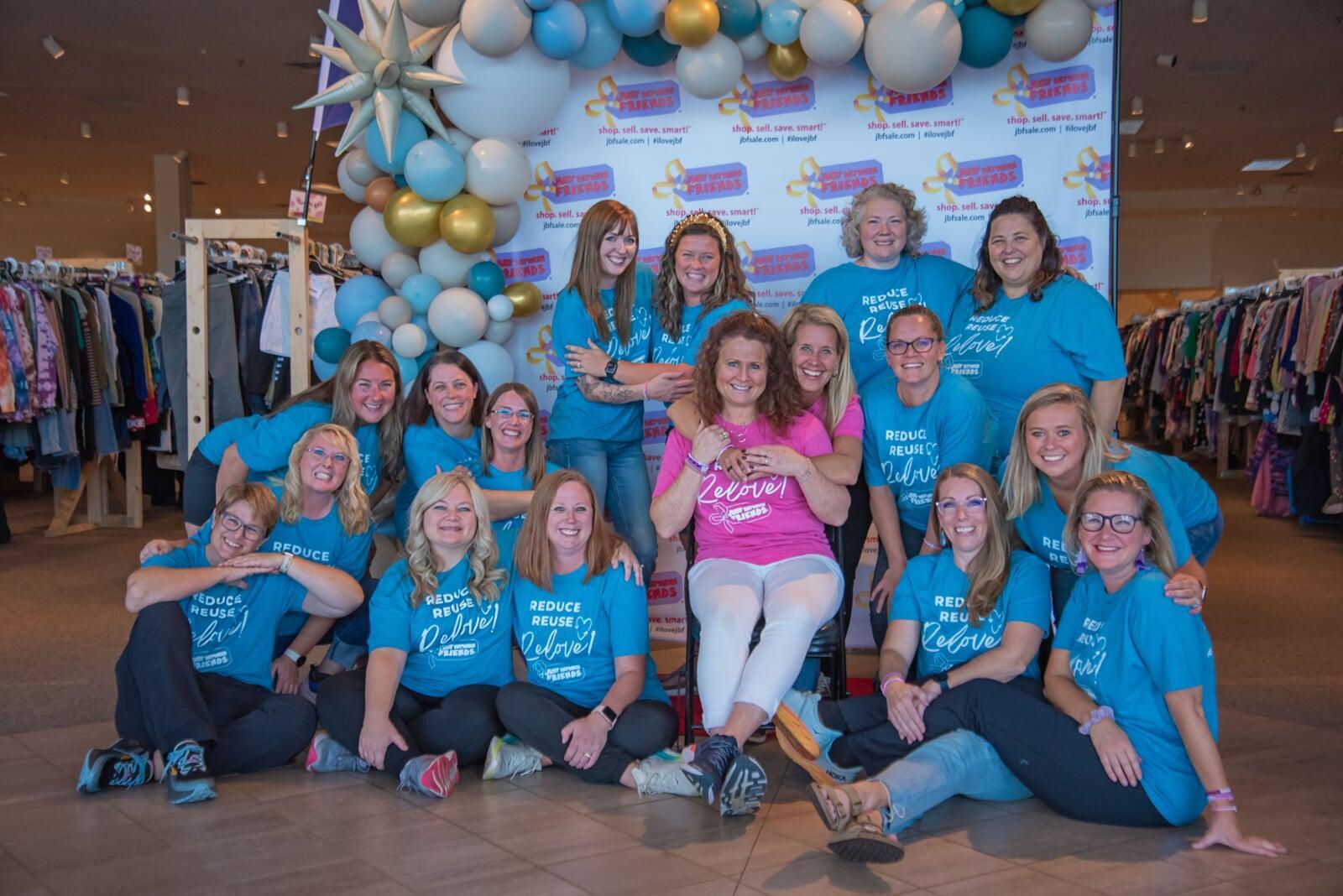 A mom and her three kids stand in front of a rack of girls clothes at their local BF sale.