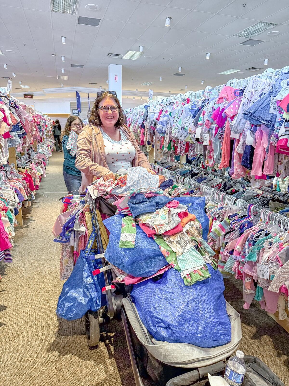A young JBF shopper mom with her daughter and a stroller full of fabulous finds