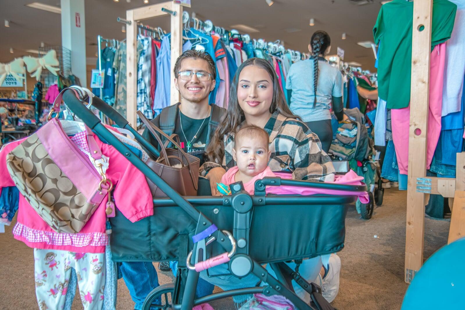 A mom and her child hug in between two rows of little girl clothes